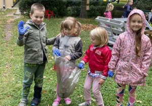 dzieci zaopatrzone w worki i gumowe rękawiczki, sprzątają osiedlowy skwerek